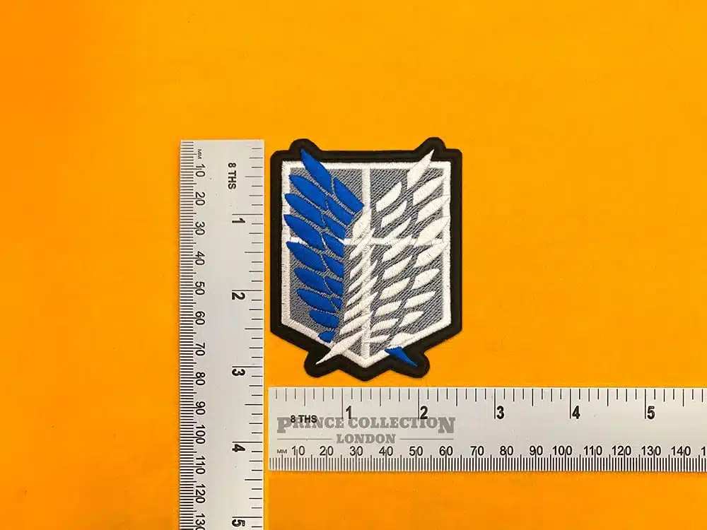 Embroidered Survey Corps wings beside measurement ruler