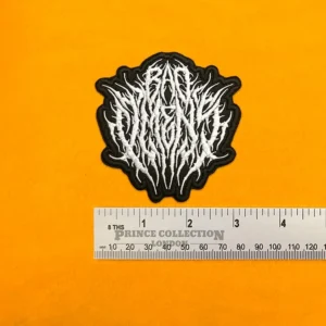 Embroidered Bad Omens logo beside measurement ruler
