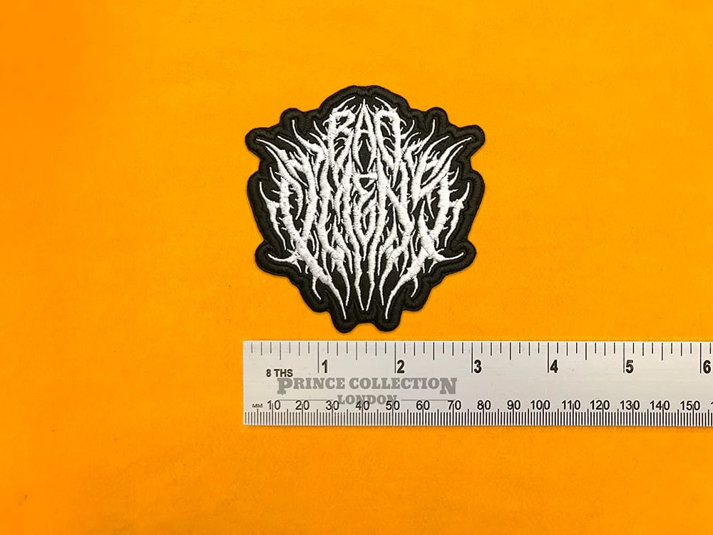 Embroidered Bad Omens logo beside measurement ruler