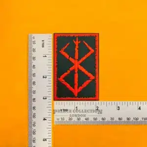 Embroidered Brand of Sacrifice symbol beside measurement ruler