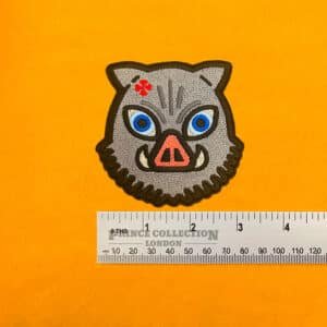 Embroidered Inosuke anime design beside measurement ruler