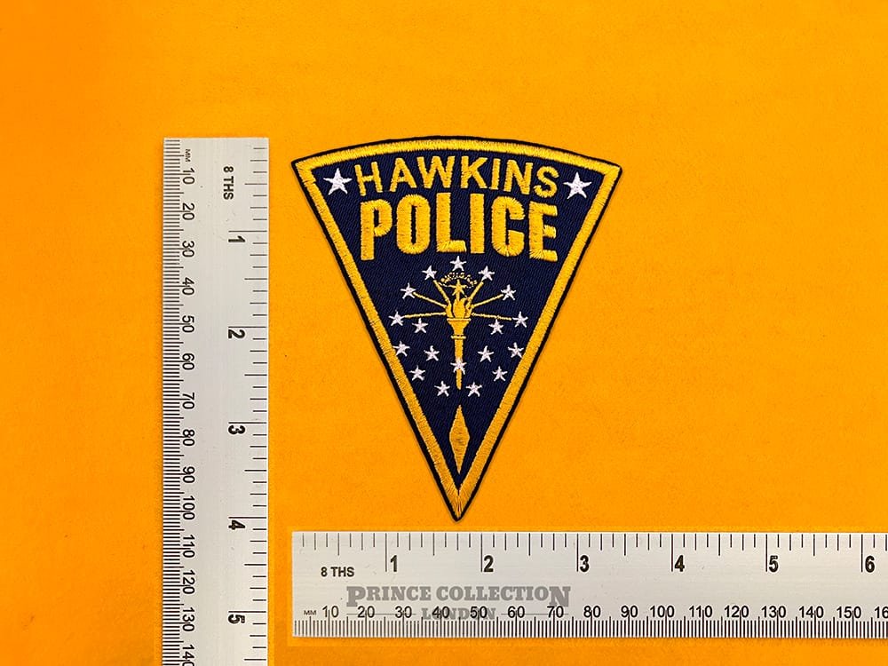 Embroidered Hawkins Police design beside measurement ruler