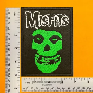 Green face embroidered punk patch beside measurement ruler