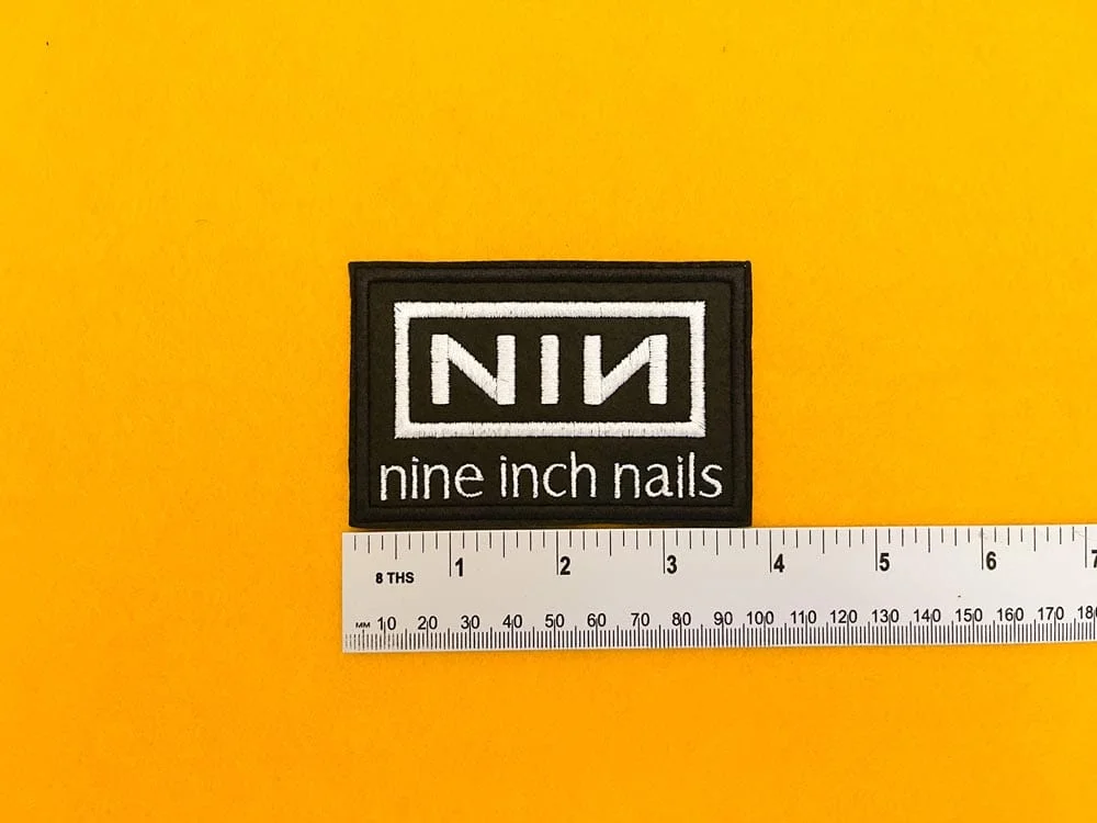 Embroidered Nine Inch Nails design beside measurement ruler
